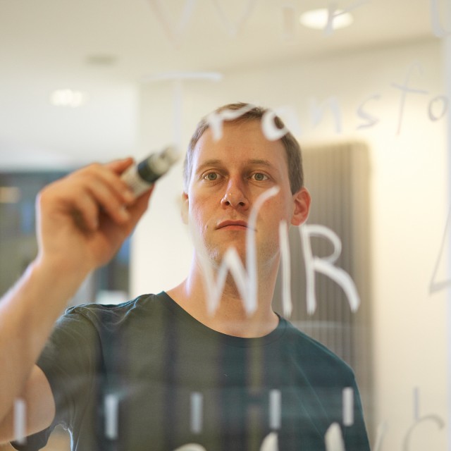 Ein Mann schreibt etwas auf eine Glasscheibe