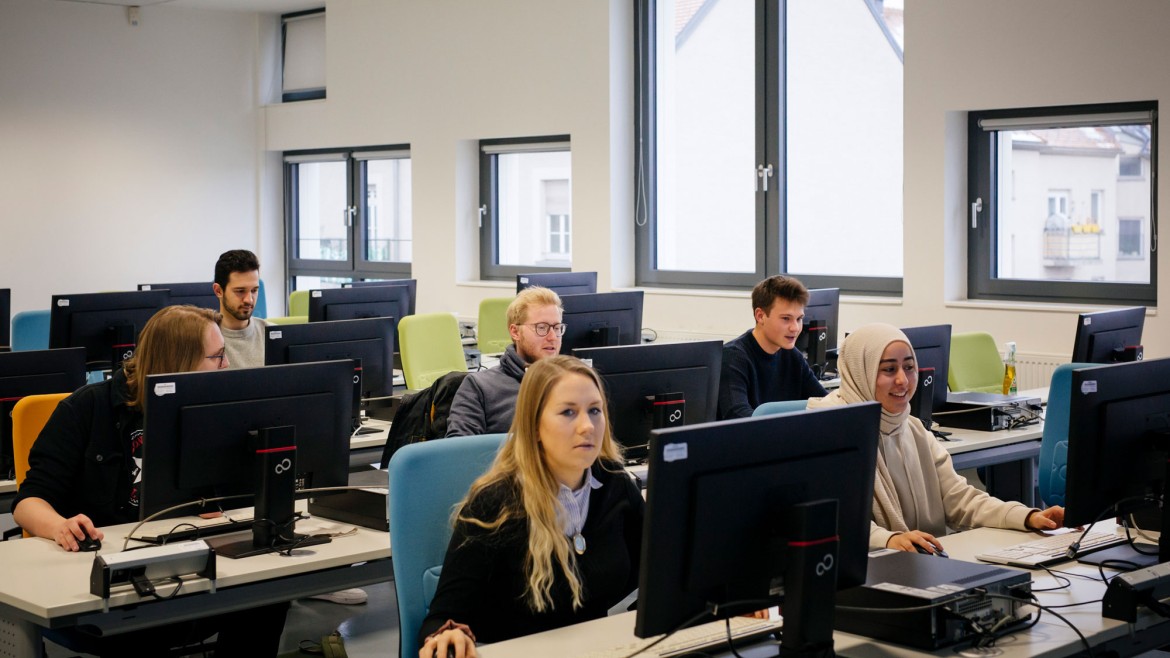 Studierende in Seminarraum vor Bildschirmen