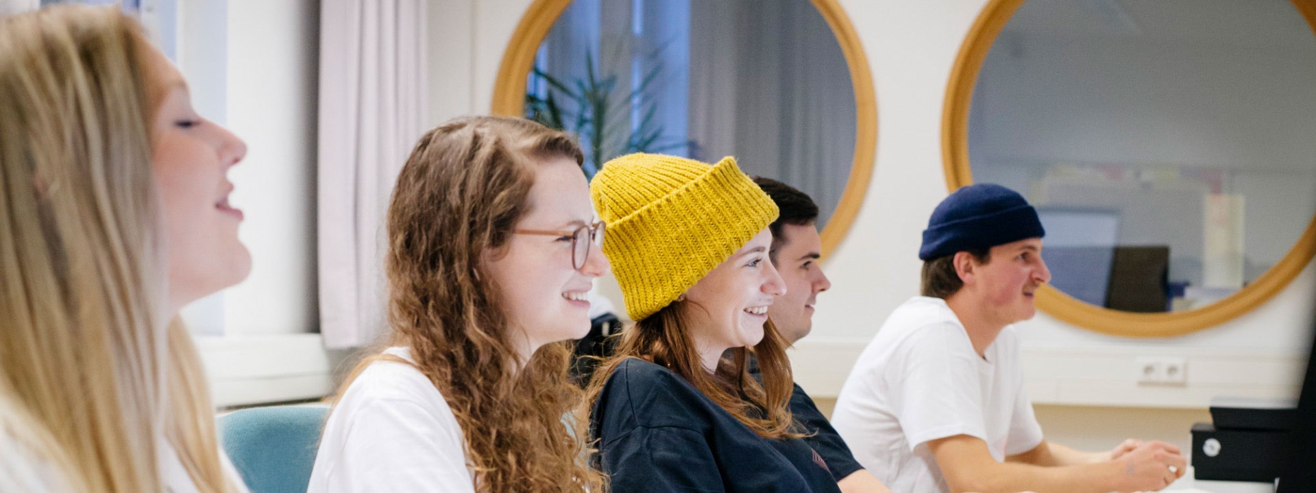 Studierende sitzen in einer Reihe vor Bildschirmen