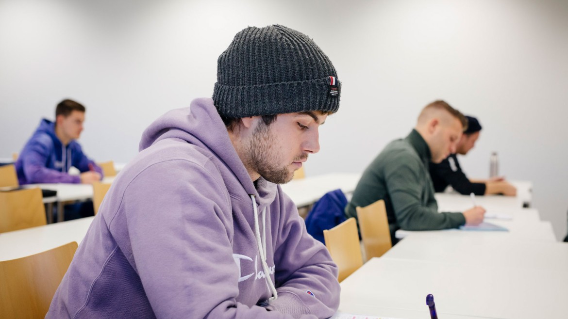 Studierender mit Mütze blickt konzentriert