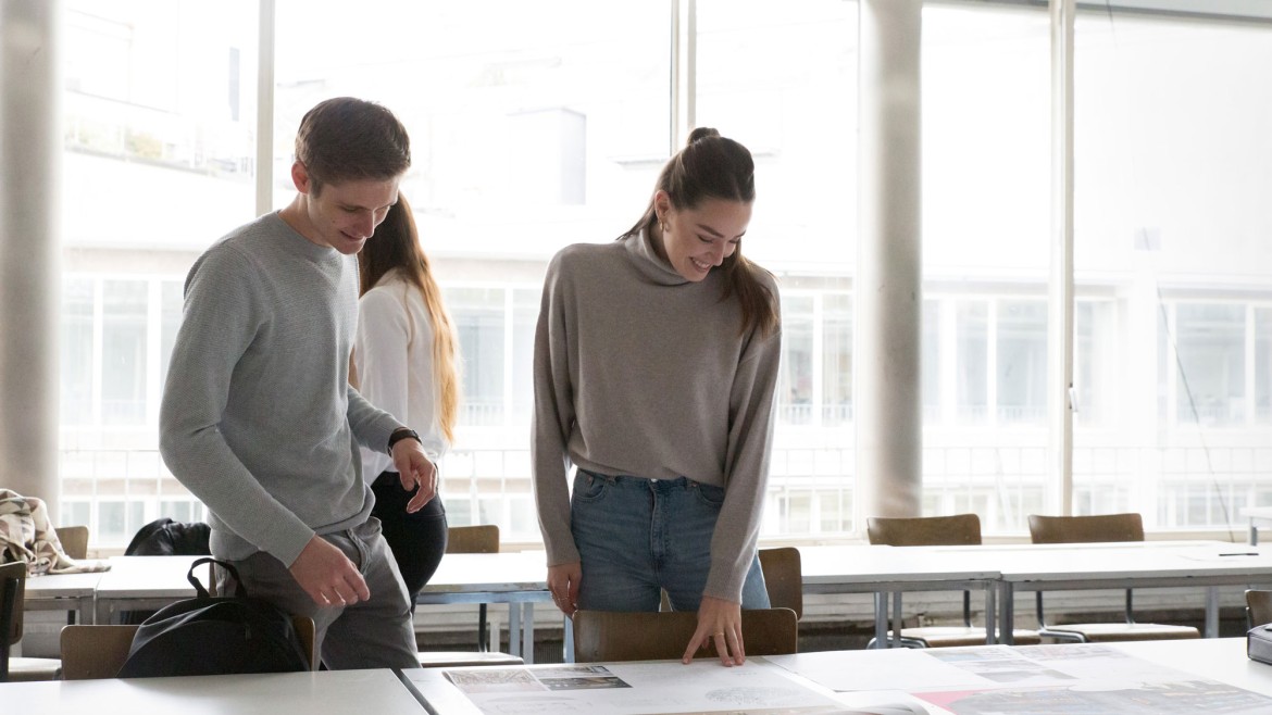 Studierende vor Skizzen auf Tisch