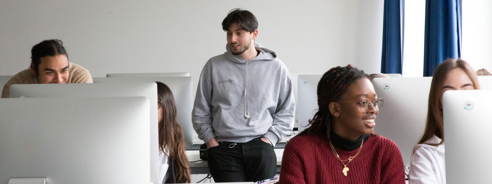 Studierende arbeiten gemeinsam vor Bildschirmen