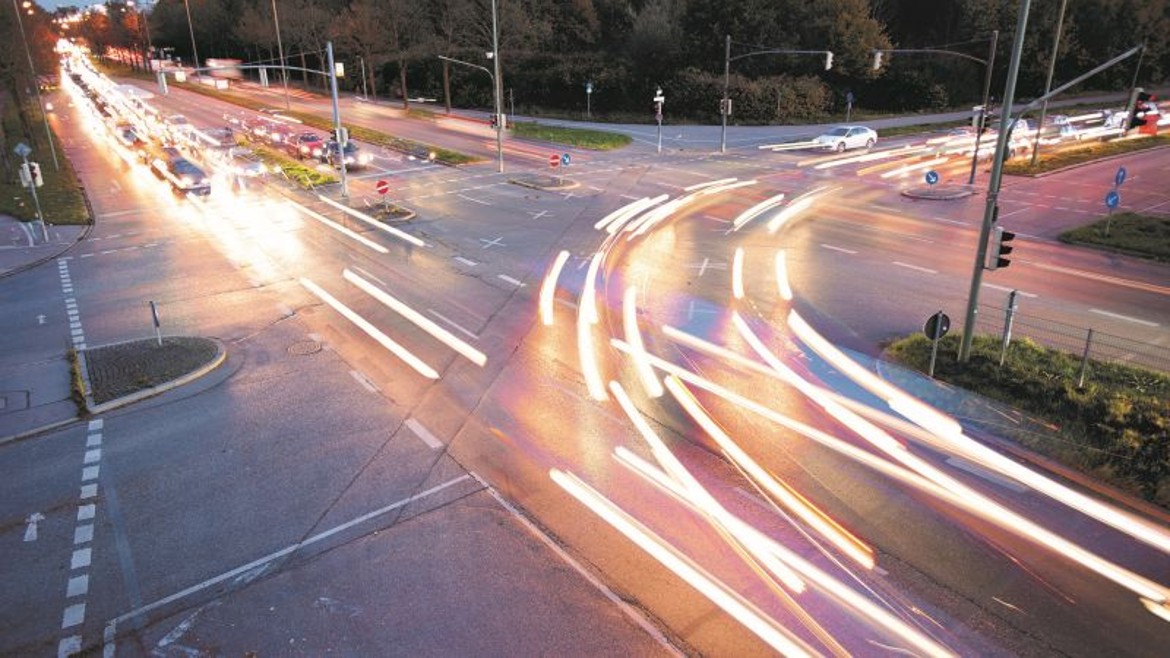 Bild einer mehrspurigen Kreuzung mit viel Verkehr in der Dämmerung.