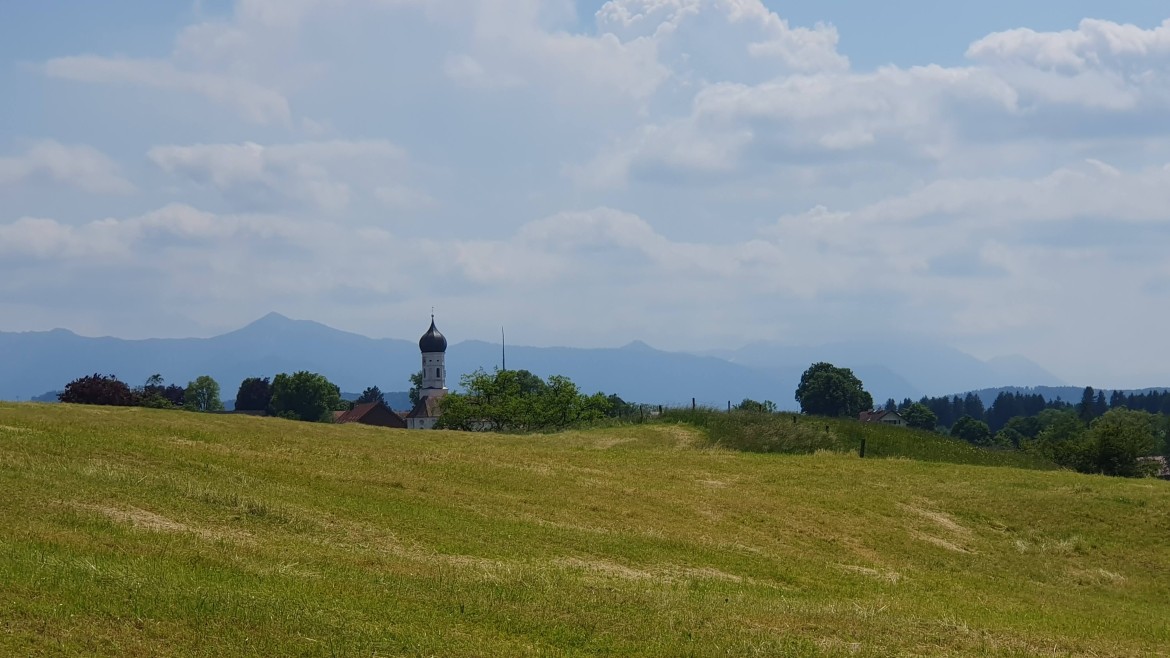 Bayernmentoring Stammtisch - Wandern im Juni 2023 (Foto: Karin Geretshauser) Landschaft mit Kirche vor den Bergen