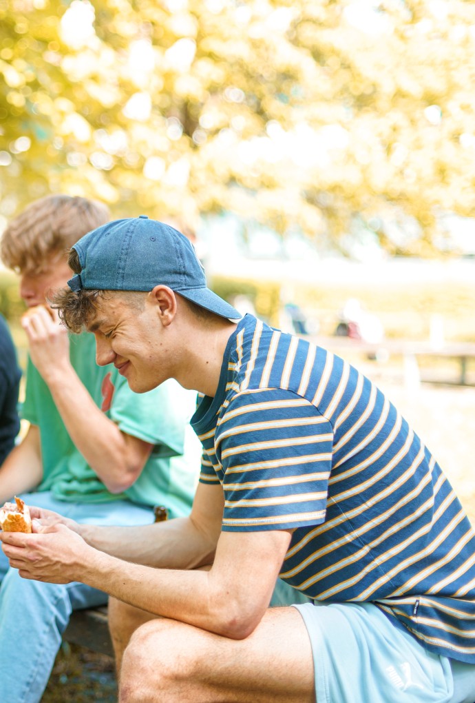 Studierende sitzen draußen und essen und trinken
