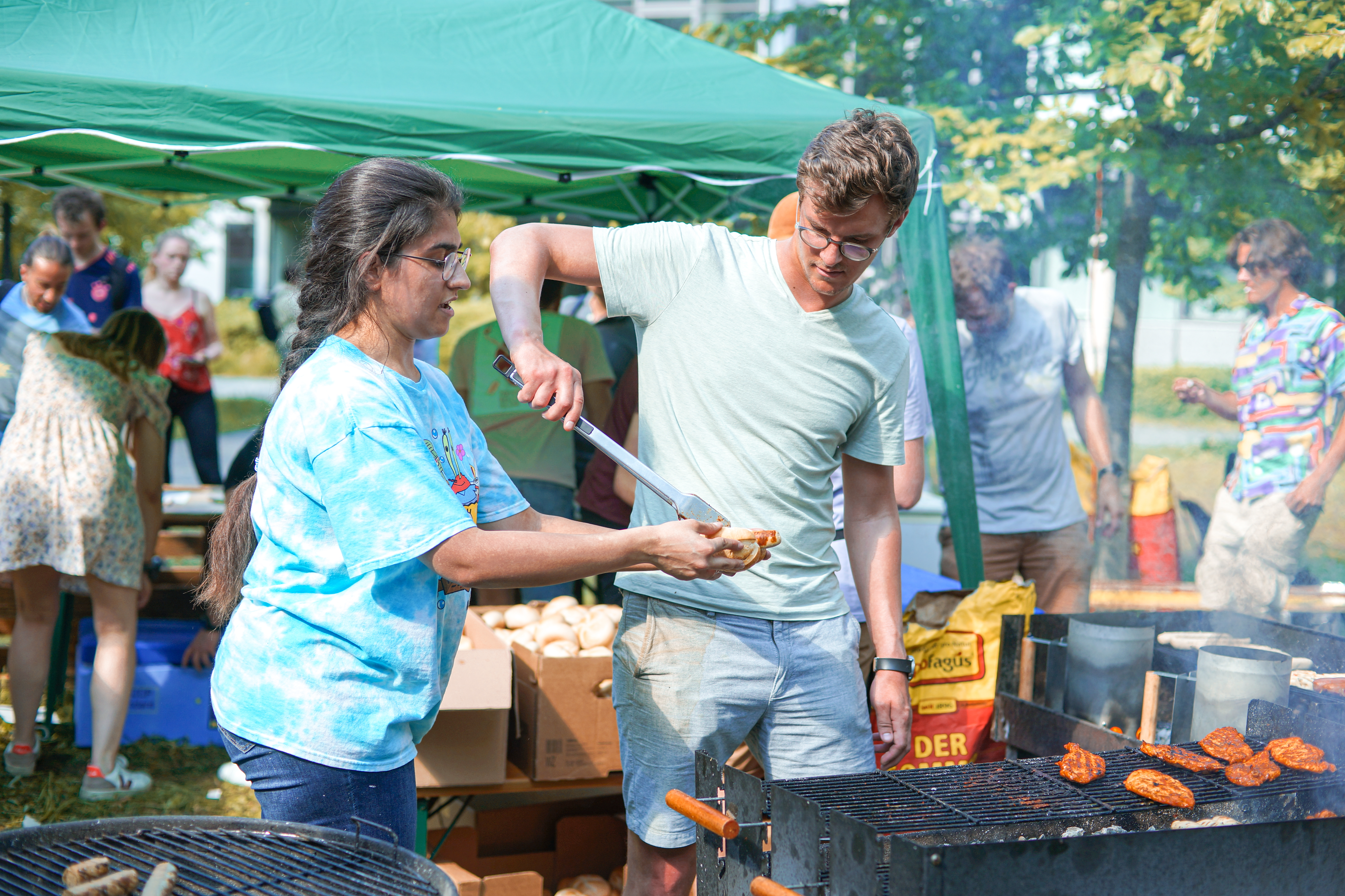 Studenten stehen am Grill und teilen Essen aus