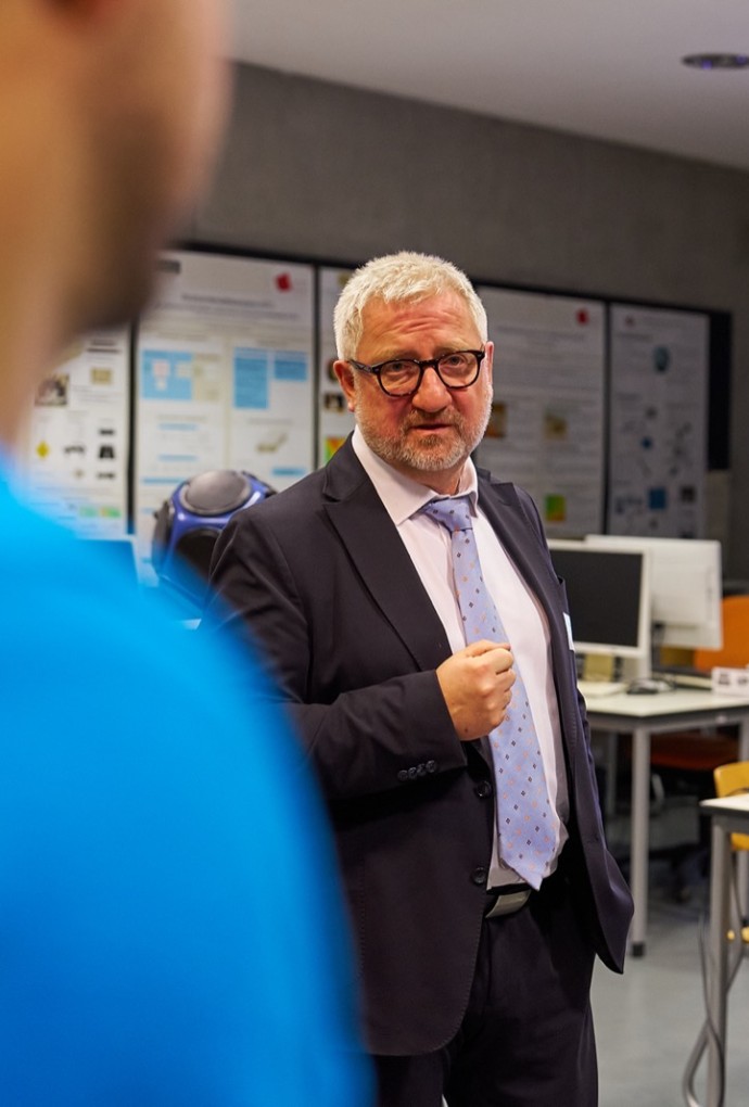 Herr Prof. Dr.-Ing. Sentpali erklärt Besucher:innen etwas.
