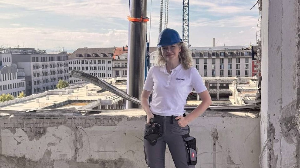 Eine Studentin steht in Arbeitskleidung auf einer Baustelle