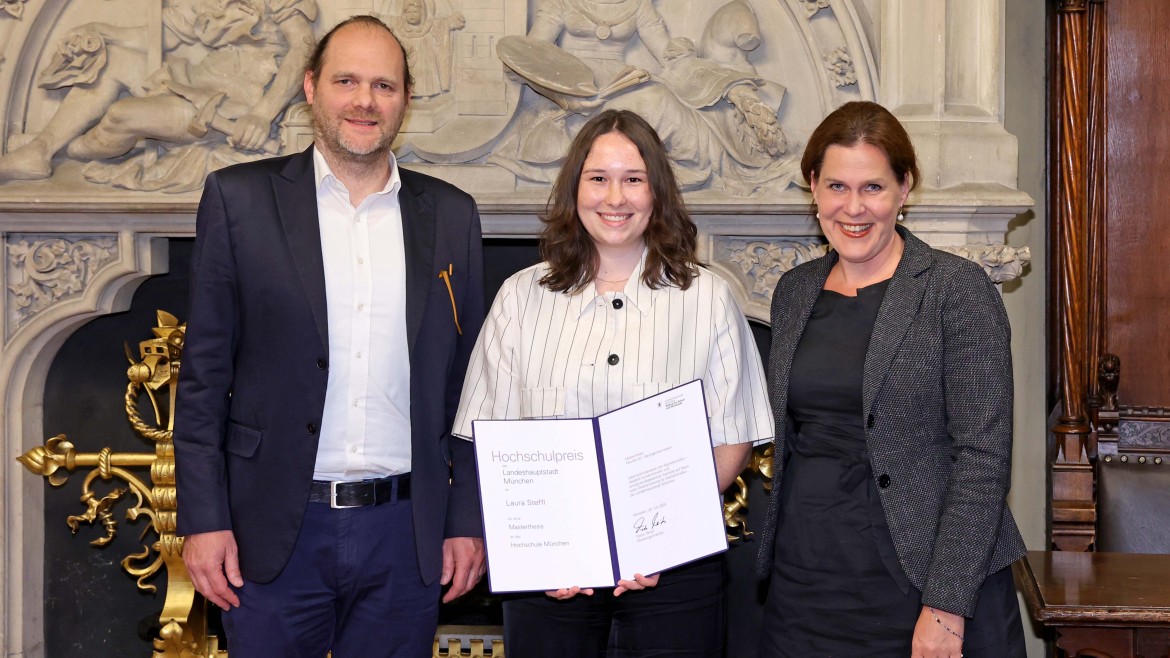 HM-Absolventin Laura Steffl erhält den Hochschulpreis der Stadt München 2025 für ihre Masterarbeit zum klimafreundlichen Straßenbau – zusammen mit HM-Professor Thorsten Stengel und Bürgermeisterin Verena Dietl.