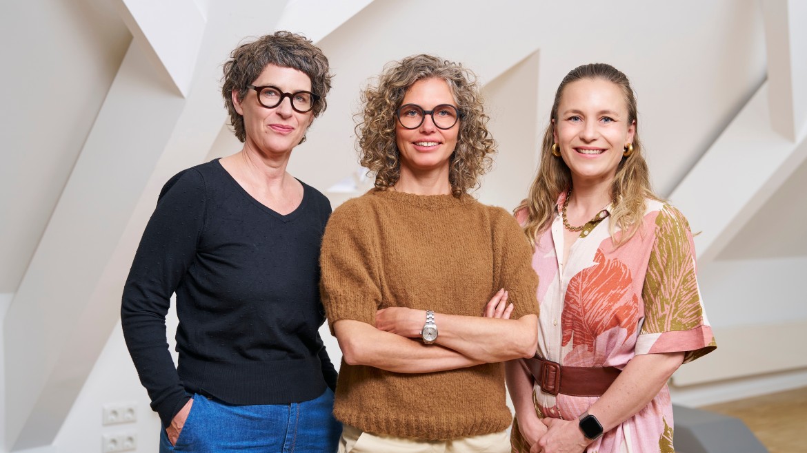 Die drei Frauenbeauftragte der Hochschule München stehen nebeneinander und blicken freundlich in die Kamera.