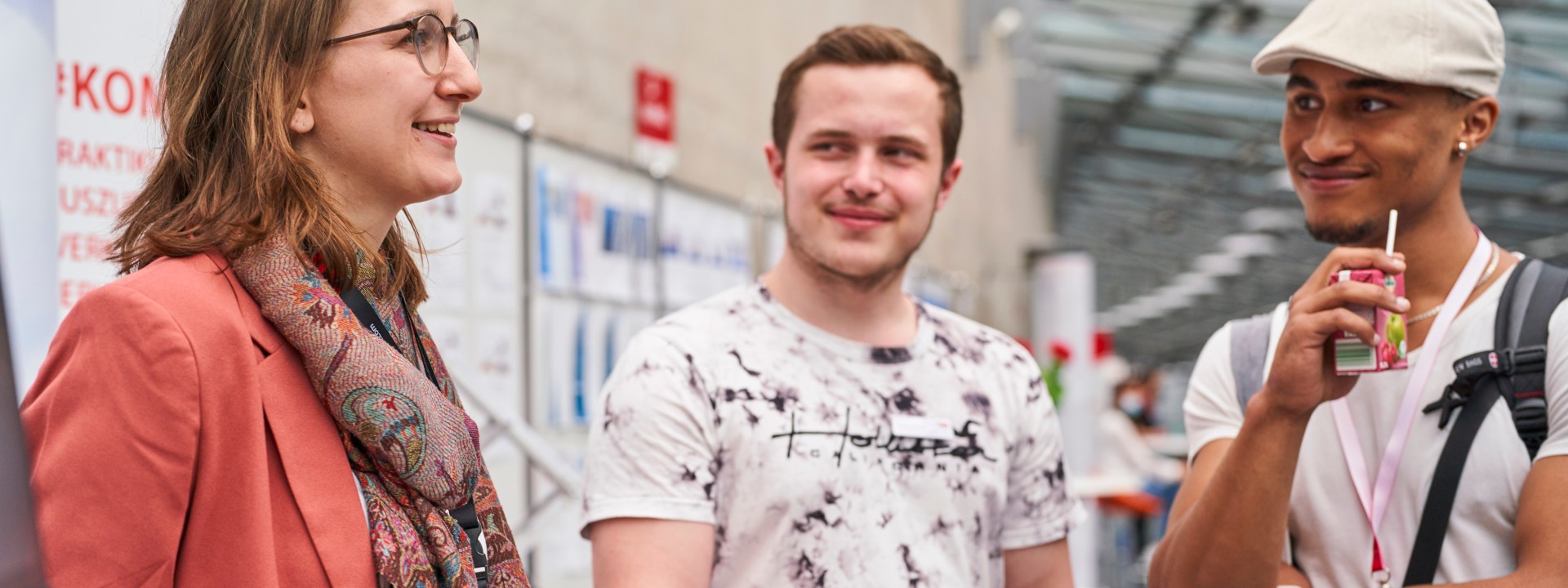 Zwei Besucher und eine Besucherin am Stand einer Messe