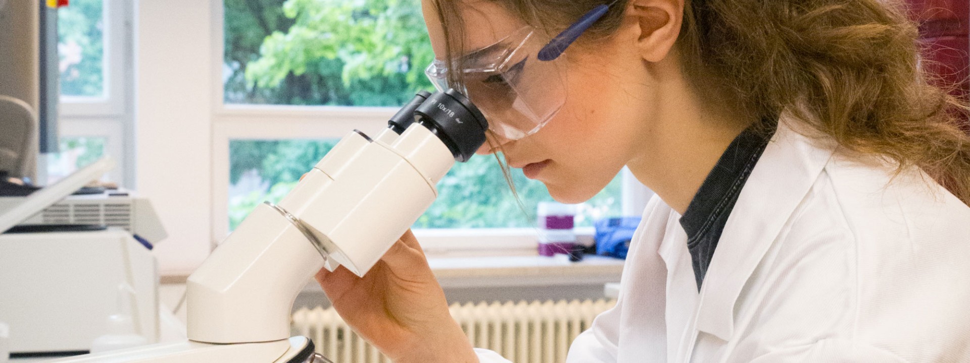 Studentin am Mikroskop im Labor für Biochemie / Mikrobiologie