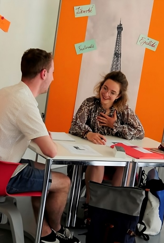 Bild der Studierenden Lola Zschiedrich sitzend und sich mit einem anderen Studierenden unterhaltend